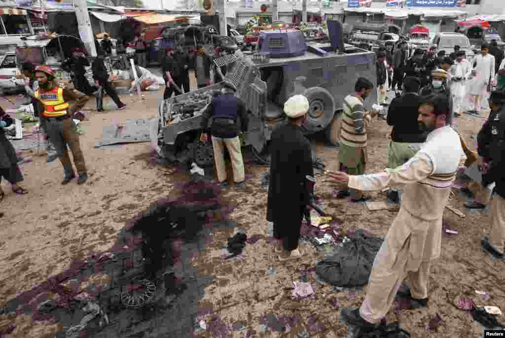 Security officials and rescue workers collect evidence at the site of a bomb blast on outskirts of Peshawar, March 14, 2014. 