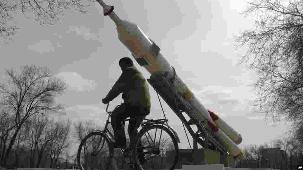 Un homme monte sur son vélo devant une fusée installée comme momument par les &nbsp;russes, le 15 mars 2016