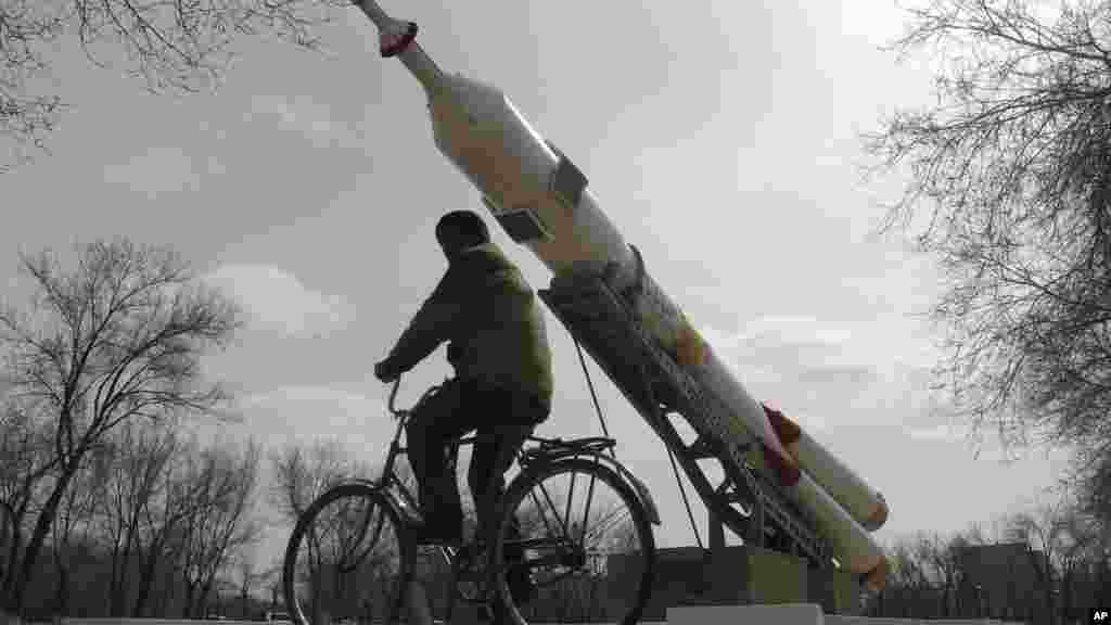 Un homme monte sur son vélo devant une fusée installée comme momument par les russes, le 15 mars 2016