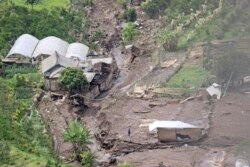 Seorang pria berdiri di tengah reruntuhan bangunan menyusul banjir bandang di Batu, Jawa Timur, Jumat, 5 November 2021. (AP)