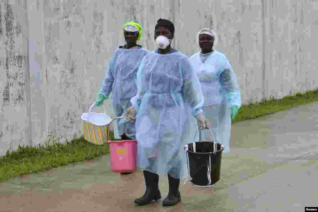 Técnicos de saúde transportam baldes de desinfectante na recém construída &quot;ilha clínica&quot; do centro de tratamento do Ébola, em Monróvia, Libéria, Set. 25, 2014. 