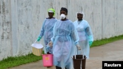 Para petugas kesehatan membawa ember-ember berisi disinfektan di pusat perawatan dan klinik Ebola di Monrovia, Liberia (25/9). (Reuters/James Giahyue)
