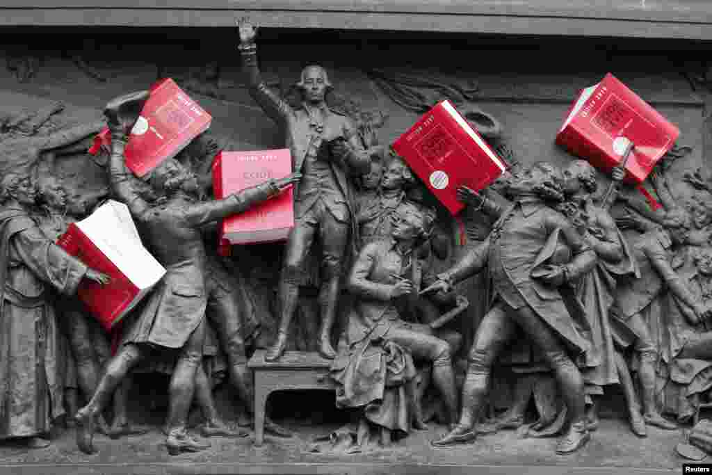 Copies of the French Civil Code are placed amongst a frieze depicting the &quot;Oath of the Jeu de Paume&quot; (June 20, 1789) on the Republic statue as French lawyers, notaries and bailiffs attend a national protest against a government reform plan to deregulate their profession in Paris, Dec. 10, 2014.