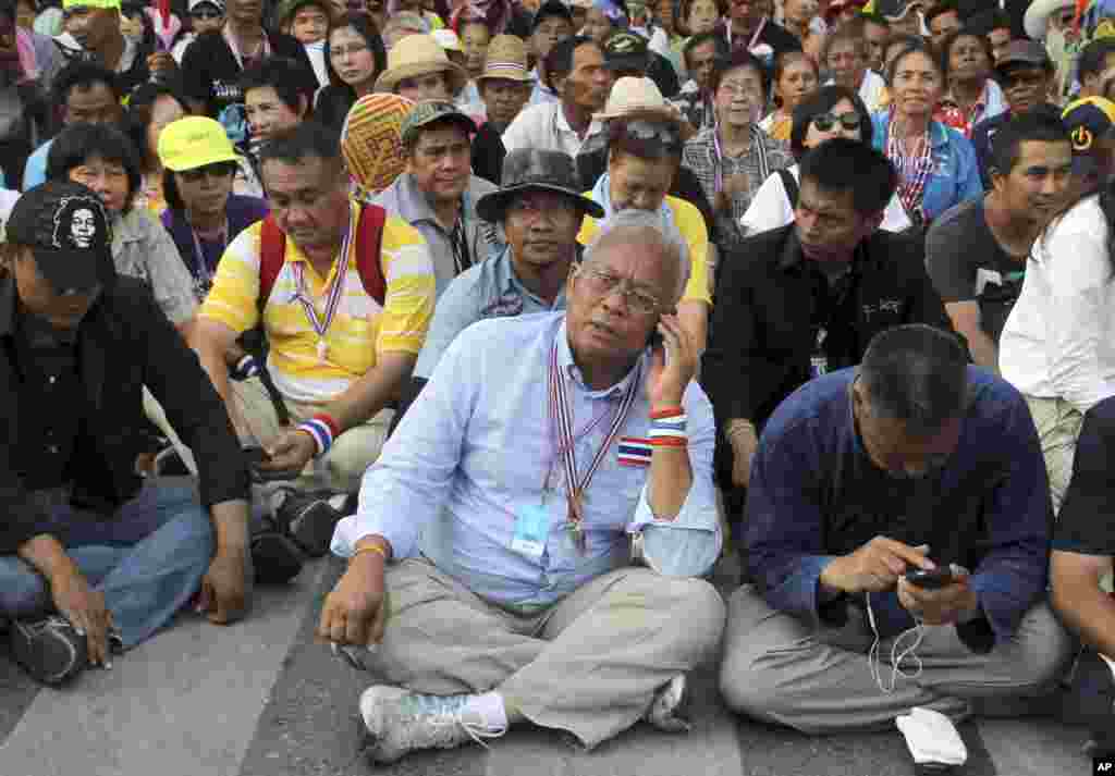 Anti-government protest leader Suthep Thaugsuban, center, talks on his mobile phone during a rally outside the parliament building, in Bangkok, May 12, 2014.