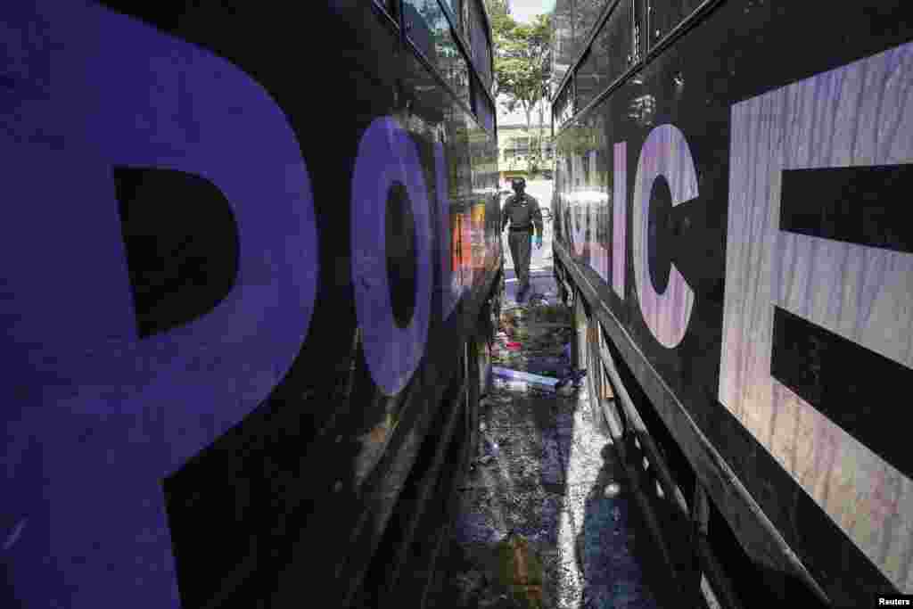 A Thai security officer inspects destroyed police trucks at the Thai-Japan youth stadium in central Bangkok, Thailand, Dec. 27, 2013. 