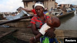 A woman sits in a canoe with her child as the metropolitan government begins the demolition of structures in the Makoko riverine community in Lagos, July 16, 2012. The structures were deemed illegal because they were built without permission on Lagos Lagoon.