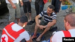 Members of Lebanese Red Cross treat a wounded man after two rockets hit his house in Beirut suburbs, May 26, 2013.
