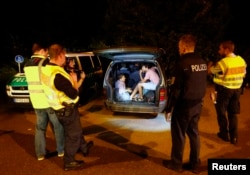 FILE - A group of migrants from Syria sits inside a vehicle stopped by German police on a country road heading to Freilassing, Germany from Salzburg, Austria Sept. 13, 2015.