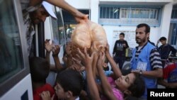 Palestinian children receive bags of bread from United Nations workers at a U.N.-run school in Rafah in the southern Gaza Strip July 19, 2014.