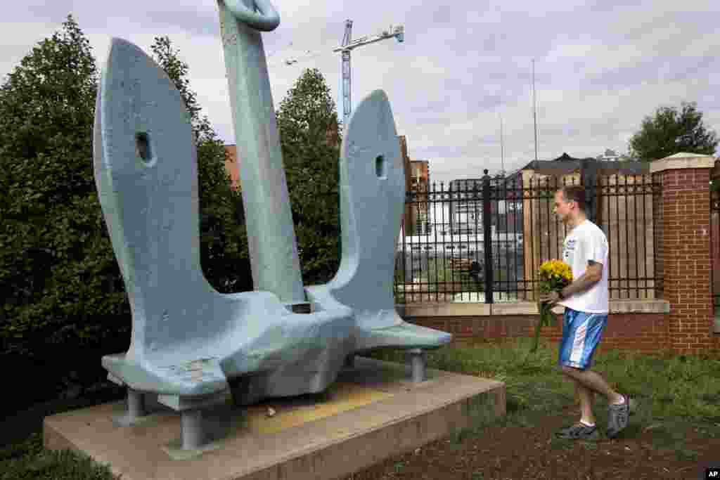 A Navy Yard employee walks to lay a bouquet of flowers by an anchor outside of the Washington Navy Yard, Sept. 17, 2013.