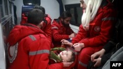 FILE - Syrian staff from the International Committee of the Red Cross evacuate a baby in Douma in the eastern Ghouta region on the outskirts of the capital Damascus, Dec. 26, 2017.
