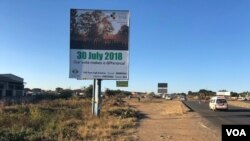 Cars and people pass a Zimbabwe Electoral Commission billboard in Harare, July 23, 2018, urging people to go and vote on July 30 and decide their future. (S. Mhofu/VOA)