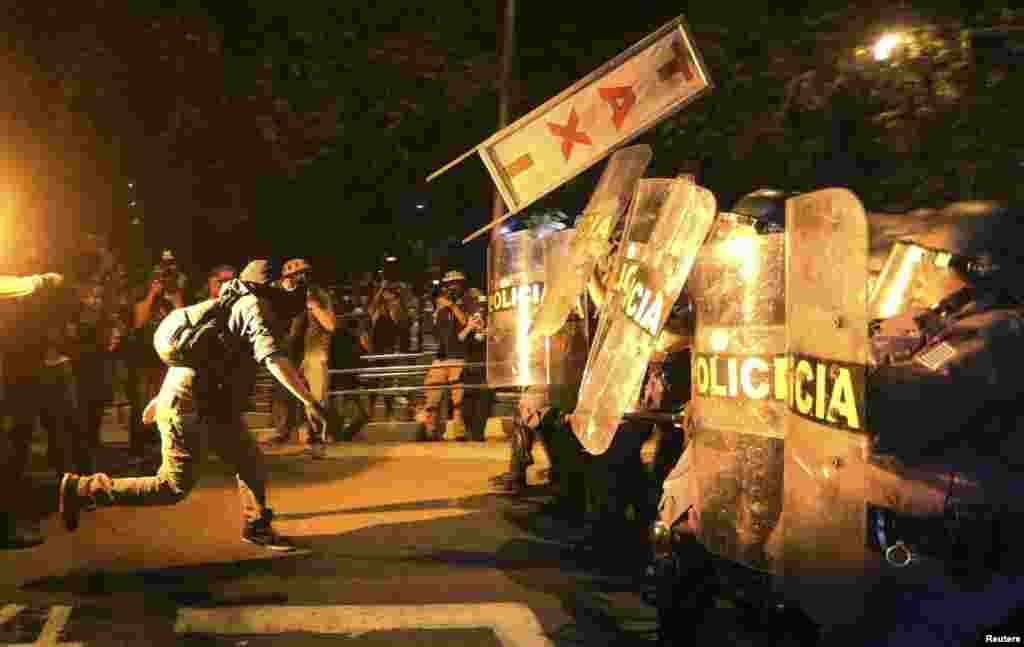 A demonstrator from the group called Black Bloc throws a taxi sign at military policemen during a protest against Sao Paulo State Governor Geraldo Alckmin, in Sao Paulo, Brazil.