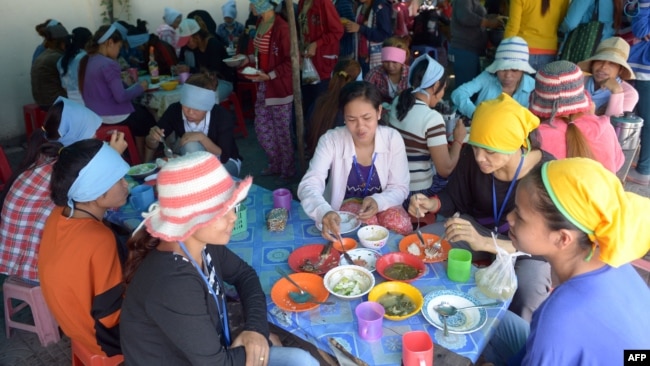 រូបឯកសារ៖ កម្មករ​រោងចក្រ​កាត់​ដេរ​សម្លៀកបំពាក់​កម្ពុជា​កំពុង​ទទួល​ទាន​អាហារ​ពេល​ថ្ងៃ​ត្រង់​នៅ​តូប​លក់​ម្ហូប​អាហារ​មួយ នៅ​ខាង​មុខ​រោងចក្រ​ដែល​ពួកគេ​ធ្វើការ ភ្នំពេញ ថ្ងៃទី៨ ខែឧសភា ឆ្នាំ២០១៤។