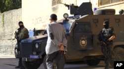 A man walks past Turkish special police personnel outside a polling station in Diyarbakir, Turkey, Nov. 1, 2015.