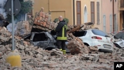 An Italian firefighter stands among rubble and destroyed cars in Modena, Italy, May 20, 2012.