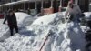 Anna Popp, 25, sits atop her snow-covered car on Guilford Avenue in Baltimore on Sunday, Jan. 24, 2016 after a storm dumped more than two feet of snow on to the city's streets.