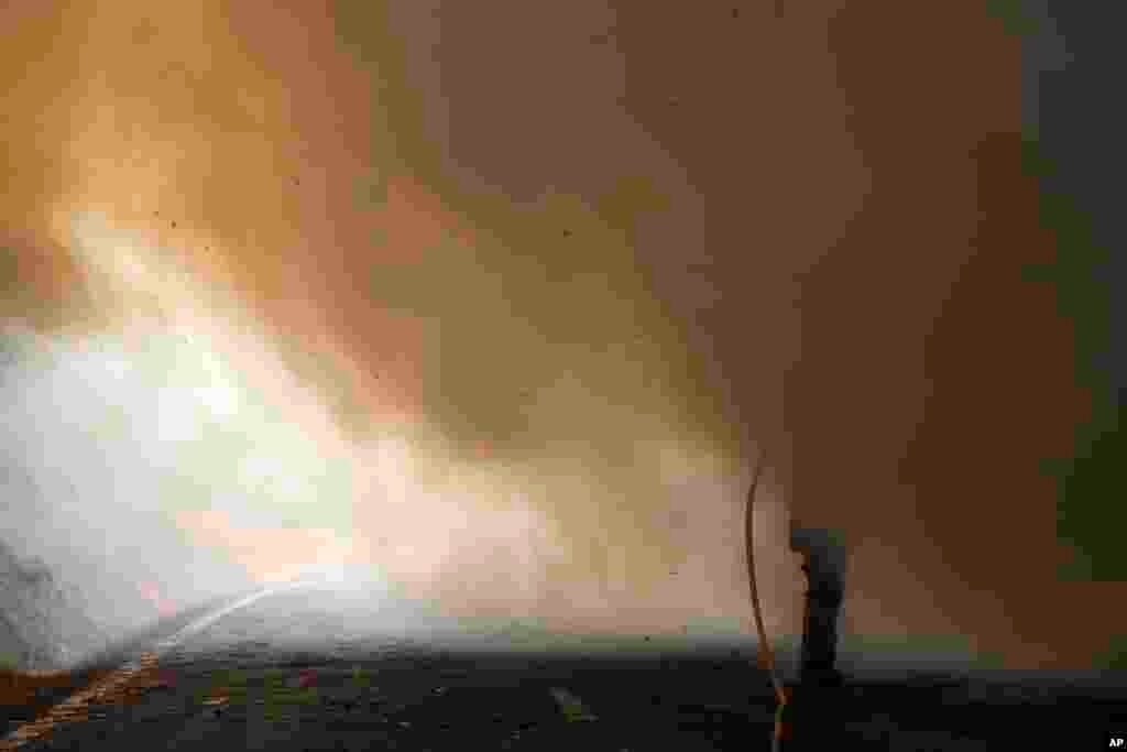 A Portuguese firefighter, surrounded by smoke, uses a hose to fight against a wildfire in Caramulo, north Portugal, Aug. 30, 2013. Portugal asked other European countries to send two more water-dropping aircraft as wildfires continue to scorch areas of forest.