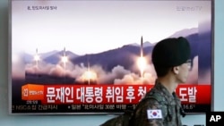 지난 14일 한국 서울역에 설치된 TV에서 북한의 미사일 시험발사 뉴스가 나오는 가운데 군인이 화면 앞을 지나고 있다.