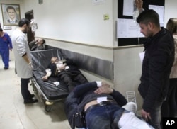 In this photo released by the Syrian official news agency SANA, Syrian injured men wait to receive medical treatments after they wounded in the main judicial building, which was attacked by a suicide bomber, in Damascus, Syria, March 15, 2017. Islamic State militants are believed to have been behind the attack.