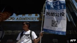 A volunteer displays a banner on a street to raise awareness of an unofficial referendum in Macau, Aug. 24, 2014. 
