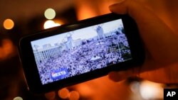 FILE - A man looks at Telegram channel NEXTA Live on his smartphone showning a rally against President Alexander Lukashenko, in Minsk, Belarus, Aug. 19, 2020. 