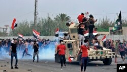 이라크 보안군이 25일 반정부 시위대에 최루탄을 발사하고 있다.