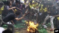 Tibetan exiles try to douse the flames from their comrade, Jamphel Yeshi, after he set himself on fire during a protest against the upcoming visit of Chinese President Hu Jintao to India in New Delhi, March 26, 2012.