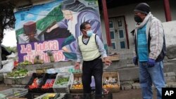 Un vendedor usando una máscara protectora para evitar la diseminación del coronavirus ofrece frutas y vegetales en una intersección en Quito, Ecuador, el 31 de marzo de 2020.