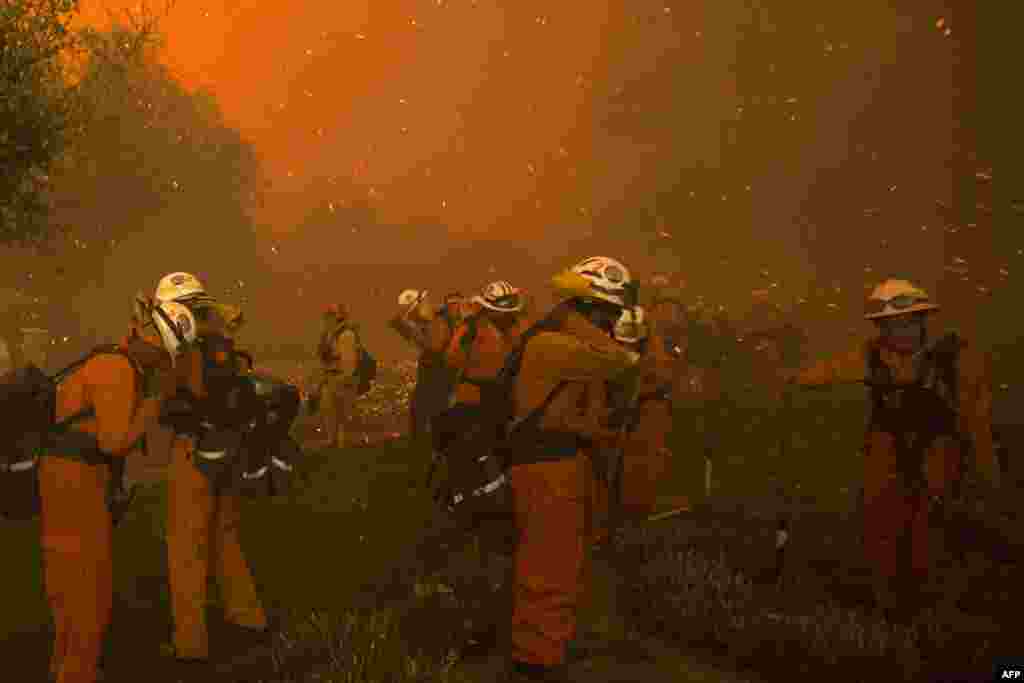 Inmate handcrew firefighters shield themselves from embers and heavy smoke as flames close in on houses at the Sand Fire near Santa Clarita, California, July 23 2016.&nbsp;&nbsp;Fueled by temperatures reaching about 108&deg; F, the wildfire began has grown to 11,000 acres.