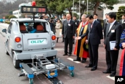 FILE - Then- President Lee Myung-bak looks at an electric vehicle while its test driving at the Korea Advanced Institute of Science and Technology or KAIST in Daejeon, South Korea, Friday, Feb. 27, 2009.