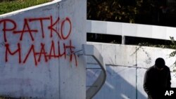 A man walks by graffiti that in Cyrillic reads "Ratko Mladic," in Belgrade, Serbia, Nov. 28, 2017