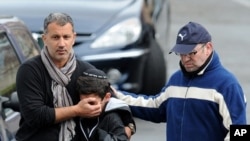 Adults comfort a boy as they walk away from the "Ozar Hatorah" Jewish school in Toulouse, southwestern France, March 19, 2012