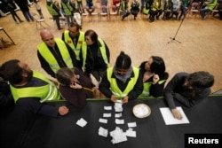 Protesters wearing yellow vests, the symbol of a French protest against higher diesel fuel prices, count ballots as they elect a representative to liaise with other blockade points, in Aubevoye, France, Dec. 6, 2018.