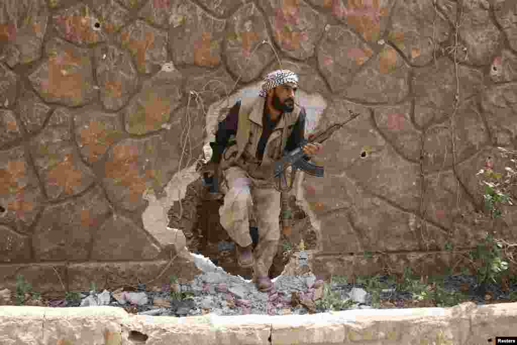 A Jaysh al-Islam (Army of Islam) rebel fighter walks through a hole in the wall, a position which they said was taken from forces loyal to Syria&#39;s President Bashar Al-Assad at the Tal-Kurdi frontline in the Eastern Ghouta of Damascus, May 10, 2015.