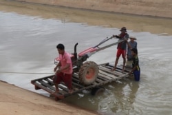 Farmers use two-wheel tractors to pump water from a twenty-kilometer irrigation system built by a Chinese company in Cambodia's western Pursat province, December 18, 2019. (Sun Narin/VOA Khmer)