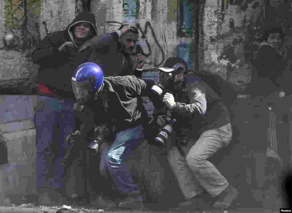 Photographers cower as protesters throw stones towards riot police near Tahrir Square, Cairo, Egypt, January 25, 2013. 