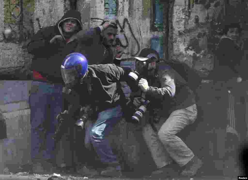 Photographers cower as protesters throw stones towards riot police near Tahrir Square, Cairo, Egypt, January 25, 2013.