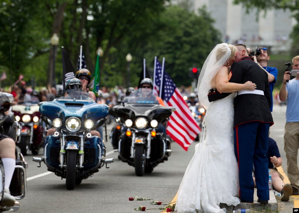 Newlyweds Tim Chambers, a U.S. Marine, and Lorraine Heist kiss as motorcycles drive past during the annual Rolling Thunder parade in Washington, D.C., May 29, 2016.