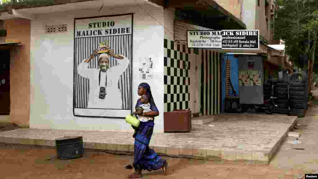 Une femme et son enfant passent devant le studio du célèbre photographe Malick Sidibé à Bamako, 15 avril 2016.