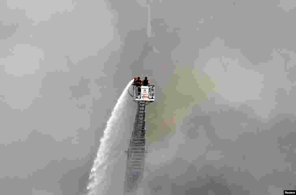 A man uses a water hose to put out the remains of a fire that broke out the day before at Beirut&#39;s port in Lebanon.