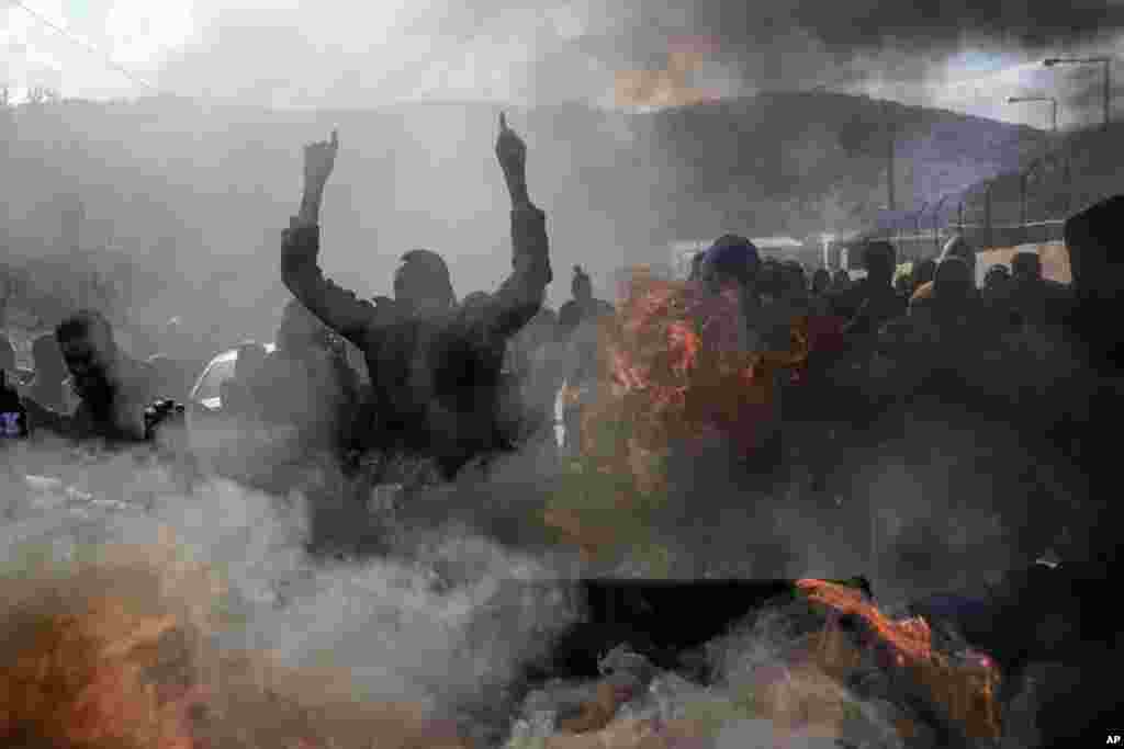 Refugees and migrants burn garbage bins and chant slogans as they demonstate outside Moria camp, following the stabbing death of a 20-year-old man from Yemen in the Greek island of Lesbos.