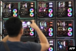 FILE - A visitor takes a picture of LED-enhanced computer motherboards during Computex 2018, at the Nangang Exhibition Center in Taipei, Taiwan, June 5, 2018.