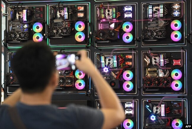FILE - A visitor takes a picture of LED-enhanced computer motherboards during Computex 2018, at the Nangang Exhibition Center in Taipei, Taiwan, June 5, 2018.