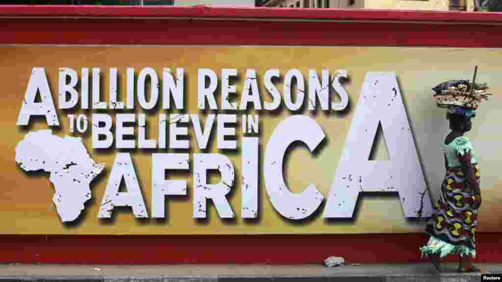 A woman walks past a billboard on a wall along a road in Nigeria's commercial capital.