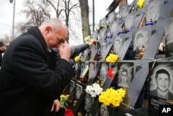 FILE - A man pays his respect at a memorial dedicated to people died in clashes with security forces at the Independent Square (Maidan) in Kiev, Ukraine, Tuesday, Nov. 21, 2017 to mark the fourth anniversary of the beginning of the protests.