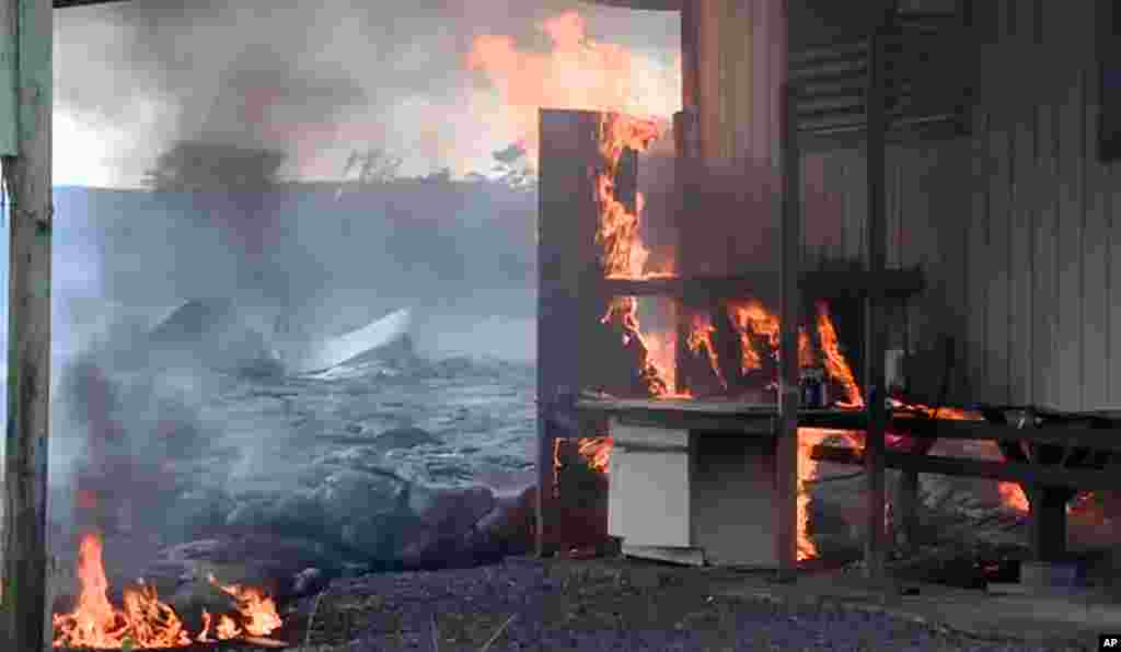 Sur&nbsp; cette image prise par le comté d&#39;Hawaii, la coulée de lave du volcan Kilauea brule une structure résidentielle le 11 novembre 2014,à Pahoa, Hawaii.