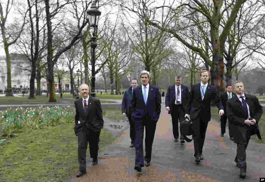 Kerry, Londra&#39;daki Yeşil Park&#39;ta yardımcıları ve korumalarıyla. Arka planda Buckhingham Sarayı g&ouml;r&uuml;l&uuml;yor. 