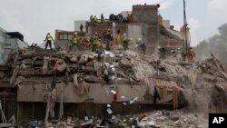 Workers shovel papers and debris off the top of the rubble of a building that collapsed in last week's 7.1 magnitude earthquake, at the corner of Gabriel Mancera and Escocia streets in the Del Valle neighborhood of Mexico City, Sept. 25, 2017.