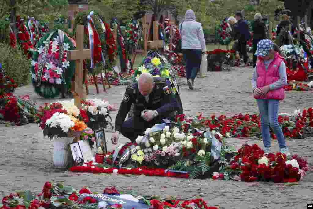 A Russian navy officer lights a candle as he pays his last respect at the grave of Captain 3rd rank Vladimir Sukhinichev, one of the 14 crew members who died in a fire on a Russian navy&#39;s deep-sea research submersible, at the Serafimovskoye memorial cemetery during a funeral ceremony in St. Petersburg, July 6, 2019. President Vladimir Putin awarded the nation&#39;s highest honors to 14 seamen who died in a fire on one of the navy&#39;s research submersibles.